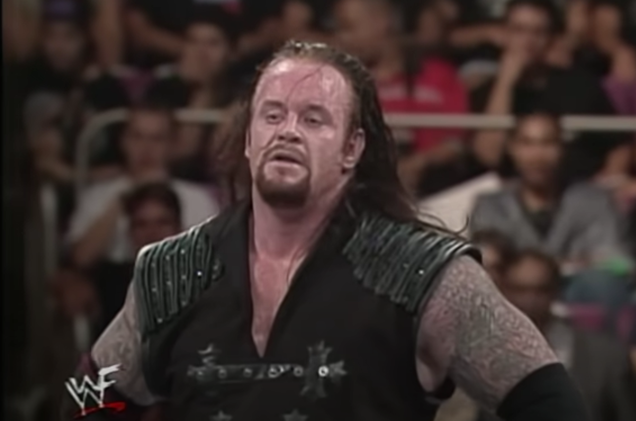 The Undertaker, hands on hips, weighs up his choices,